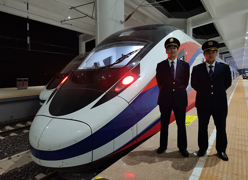 劉銀能（右一）與中國(guó)師父鄔俊鴻在動(dòng)車組前合影。受訪者供圖