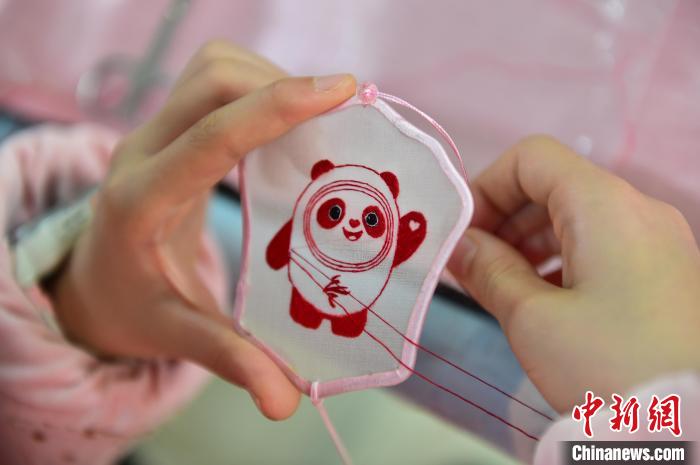 圖為一名小學(xué)生正在繡制2022年北京冬奧會(huì)吉祥物“冰墩墩”形象?！∮髟屏?攝