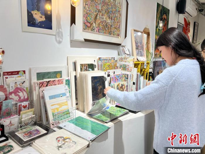 圖為藝術(shù)品商店內(nèi)，顧客挑選插畫作品?！＄婌?攝