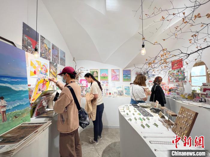 圖為藝術(shù)品商店內(nèi)，顧客挑選插畫作品?！＄婌?攝