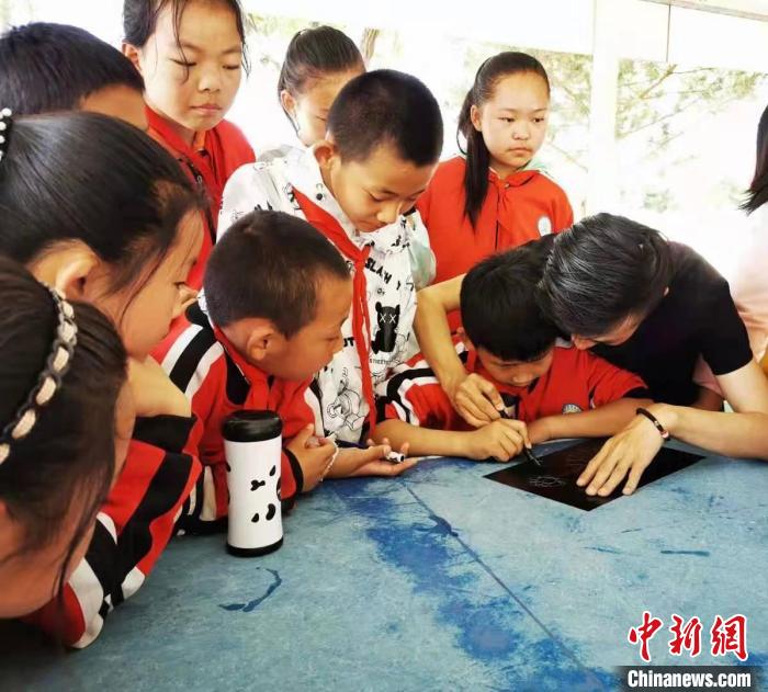 圖為朱增平(右一)教學(xué)生創(chuàng)作鍥金畫。(資料圖) 受訪者供圖