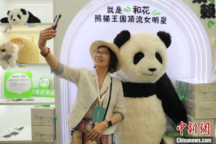 美國(guó)華視總裁楊蓮花與大熊貓文創(chuàng)產(chǎn)品合影。　王磊 攝