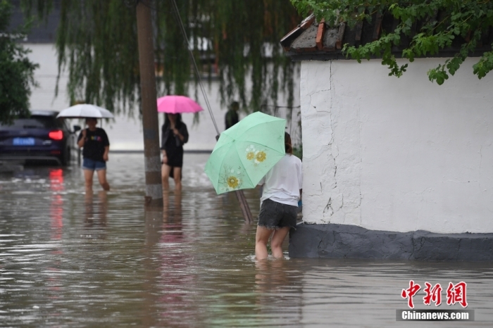 7月31日，市民行走在雨中的北京房山區(qū)瓦窯頭村。北京市氣象臺(tái)當(dāng)日10時(shí)發(fā)布分區(qū)域暴雨紅色預(yù)警信號(hào)。北京市水文總站發(fā)布洪水紅色預(yù)警，預(yù)計(jì)當(dāng)日12時(shí)至14時(shí)，房山區(qū)大石河流域?qū)⒊霈F(xiàn)紅色預(yù)警標(biāo)準(zhǔn)洪水。<a target='_blank' href='/'><p  align=