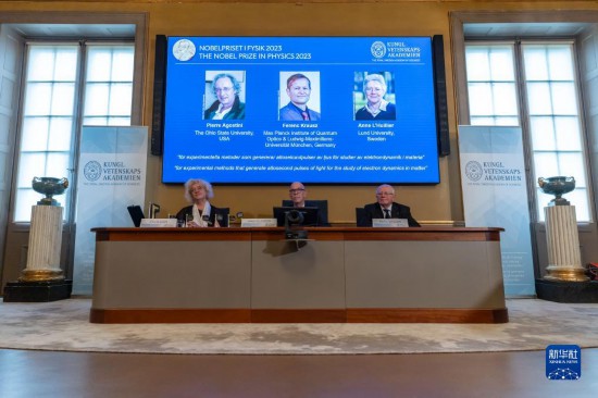 10月3日，在瑞典斯德哥爾摩舉行的2023年諾貝爾物理學(xué)獎公布現(xiàn)場，屏幕上顯示獎項(xiàng)得主皮埃爾·阿戈斯蒂尼（左）、費(fèi)倫茨·克勞斯（中）和安妮·呂利耶的照片。新華社發(fā)（魏學(xué)超攝）