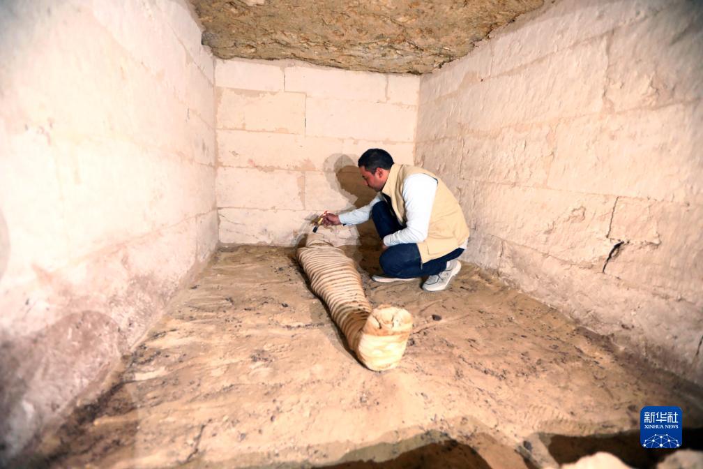 10月15日，在埃及明亞省考古現(xiàn)場，考古人員清理一座石鑿墓中的木乃伊。新華社發(fā)（艾哈邁德·戈馬攝）