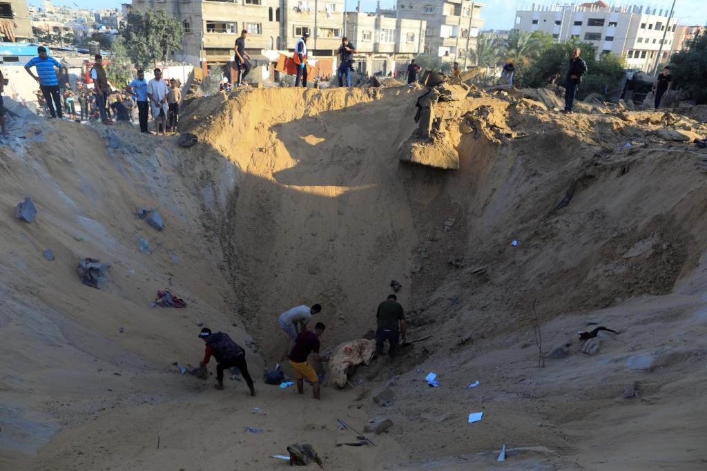 10月16日，在加沙地帶南部城市汗尤尼斯，人們在遭以色列襲擊后的建筑廢墟中救援傷者。 新華社發(fā)（亞西爾·庫迪 攝）