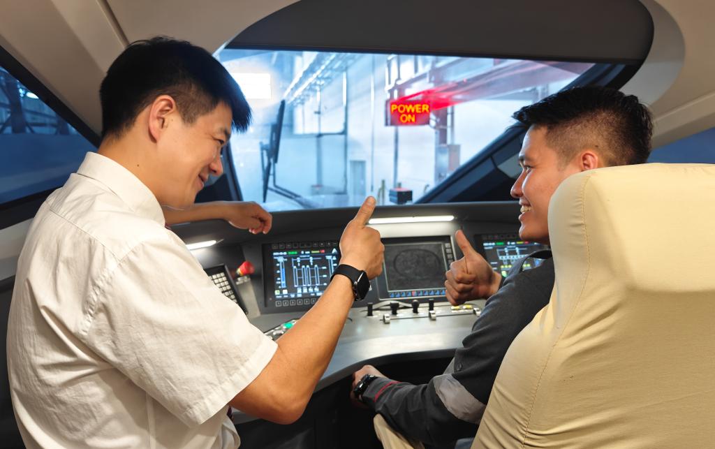 8月25日，在印度尼西亞萬隆的雅萬高鐵德卡魯爾動車所內，中國師傅穆振（左）在向印尼火車司機塞蒂亞萬講解動車組出庫前的上電作業(yè)。