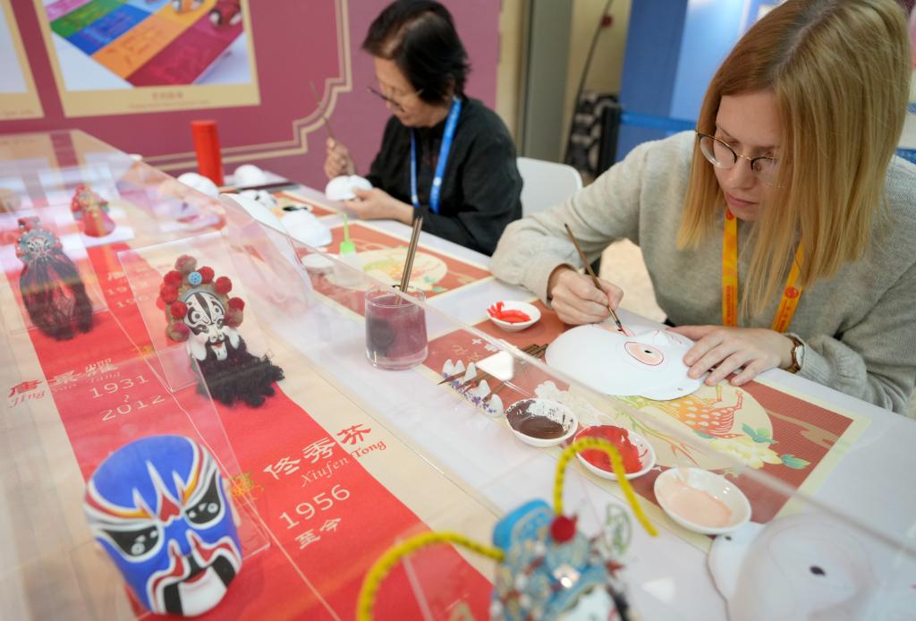 10月16日，在第三屆“一帶一路”國(guó)際合作高峰論壇新聞中心，來(lái)自比利時(shí)的記者（右）體驗(yàn)畫(huà)京劇臉譜。新華社記者 王毓國(guó) 攝