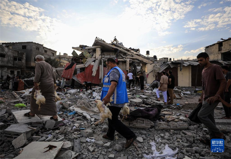 10月27日，在加沙地帶南部城市汗尤尼斯，人們經(jīng)過以軍襲擊后的房屋廢墟。