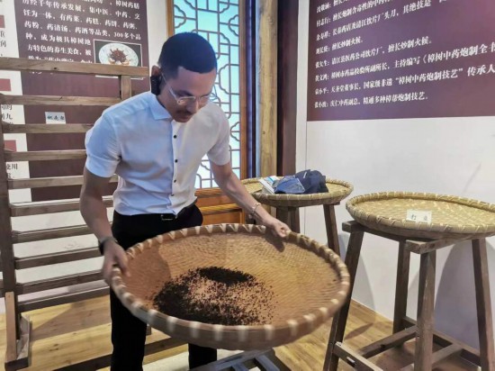 2023“一帶一路”媒體合作論壇聯(lián)合采訪團團員在非遺文化展示館體驗中藥炮制技藝。（本報記者 黃超攝）