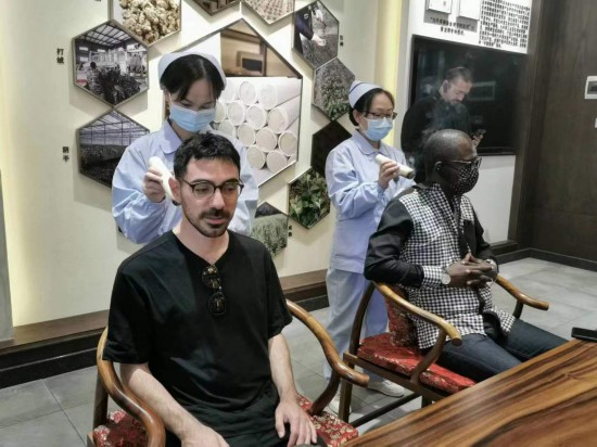 2023“一帶一路”媒體合作論壇聯(lián)合采訪團團員在九牛草展示館體驗艾灸。（本報記者 黃超攝）
