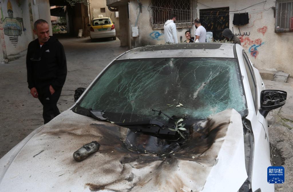 12月17日，在約旦河西岸城市圖勒凱爾姆附近的一處難民營，人們查看在沖突中損毀的車輛。新華社發(fā)（尼達(dá)爾·艾仕塔耶?dāng)z）