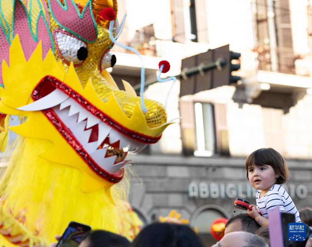 2月18日，在意大利羅馬，一名小朋友在彩妝巡游上觀看舞龍。新華社記者 李京 攝