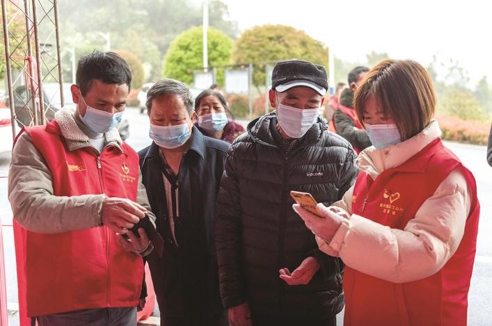 長(zhǎng)沙縣黨員志愿者正在幫助參與核酸檢測(cè)的群眾掃描“場(chǎng)所碼”。劉思源 攝