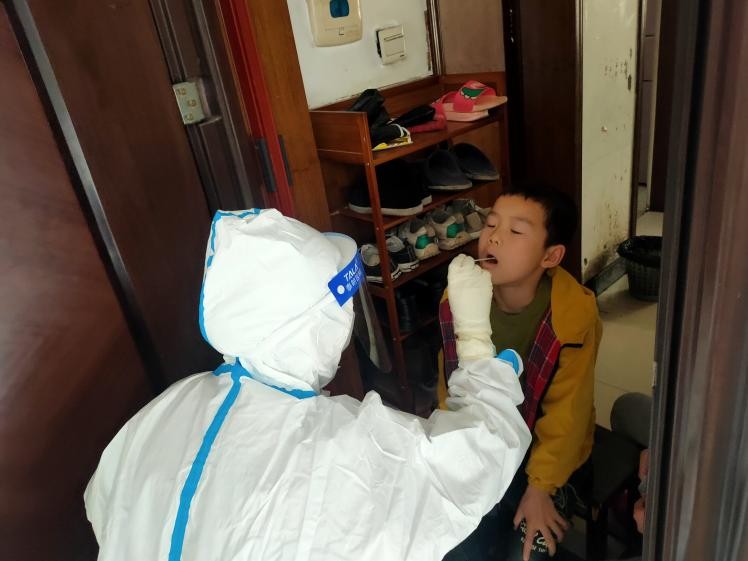 醫(yī)務(wù)工作者為封控區(qū)的居民上門(mén)采樣核酸。單位供圖