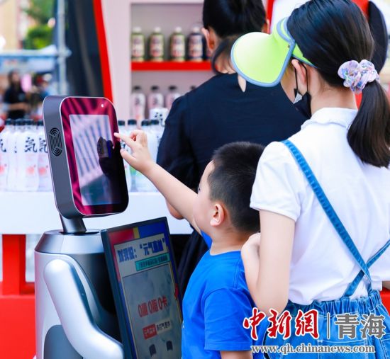 圖為一名小朋友正在和機(jī)器人“志愿者”進(jìn)行互動(dòng)。 沐聞 攝