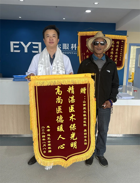 達(dá)瓦老人向吳四華（左）贈送錦旗。受訪者供圖