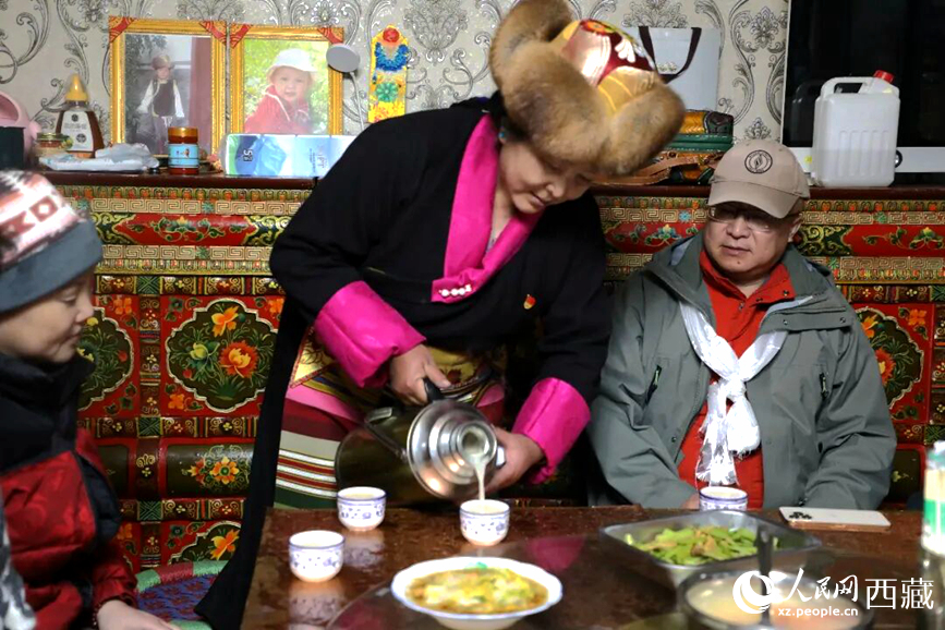 扎西曲登社區(qū)的居民在家中熱情招待遠道而來的游客。居民身著盛裝，為游客倒上熱騰騰的酥油茶，桌上擺放著切瑪與特色美食，賓主共話民族團結情誼。人民網(wǎng)記者 吳雨仁攝