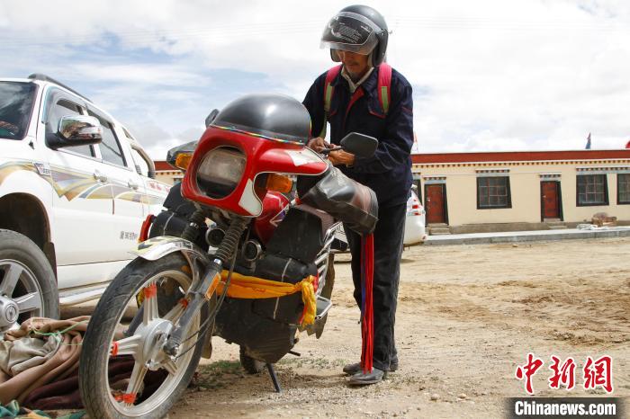 圖為白瑪準(zhǔn)備騎摩托車巡湖。　趙朗 攝