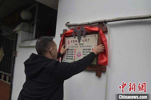 桂溪鎮(zhèn)渭溝村政府工作人員為“十星級文明戶”掛上牌匾?！钣?攝