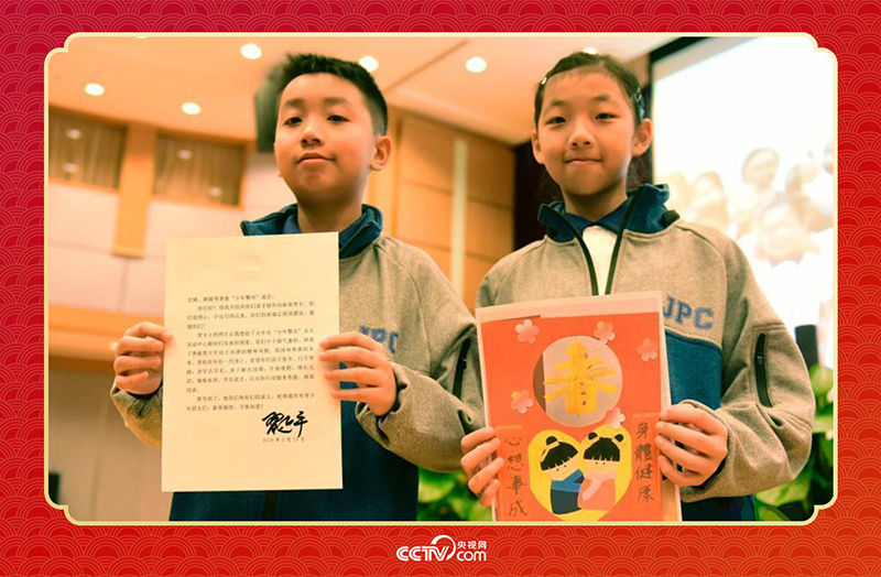 圖為香港“少年警訊”成員郭宏晞（左）展示習(xí)主席回信、羅顥凝（右）展示送給習(xí)主席的賀卡并合影。