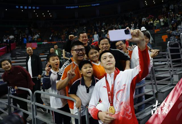 11月12日，十五運(yùn)會男籃成年組決賽，廣東隊(duì)獲得冠軍后，胡明軒與球迷們合影留念。張由瓊 攝