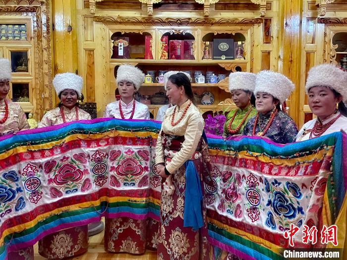 圖為女性展示村民自發(fā)繡制的“百米五彩哈達”?！±钣穹?攝