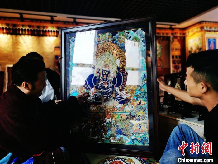 圖為久美尖措(左)與徒弟們展示唐卡作品。　張?zhí)砀?攝
