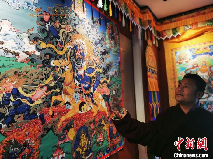 圖為久美尖措展示唐卡作品?！?zhí)砀?攝
