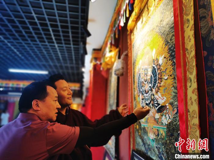 圖為久美尖措展示唐卡作品?！?zhí)砀?攝