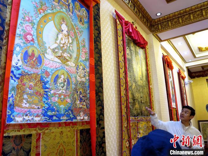 圖為完德尖措展示熱貢龍樹(shù)畫(huà)苑內(nèi)的唐卡?！?zhí)砀?攝