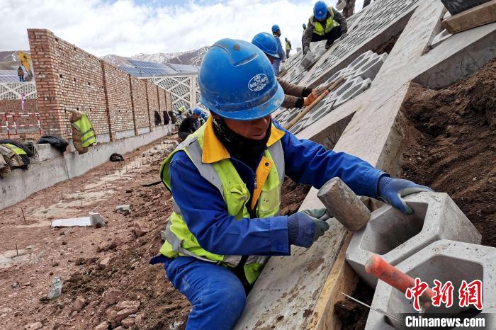 圖為光伏發(fā)電項(xiàng)目施工區(qū)工人在護(hù)坡鋪設(shè)空心磚。　李雋 攝