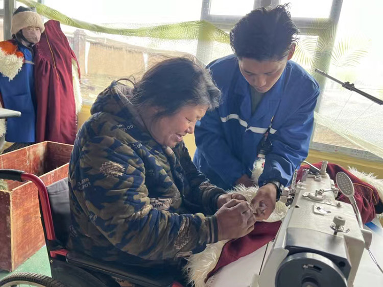 扎西奪爾登幫助殘疾員工裁剪。阿壩州文明辦供圖