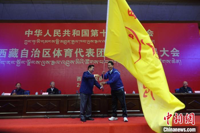西藏自治區(qū)副主席甲熱·洛桑丹增授代表團(tuán)團(tuán)旗，西藏自治區(qū)體育局局長(zhǎng)尼瑪次仁接旗?！∪轿木?攝