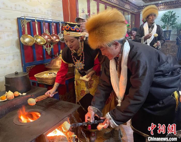 圖為人們在火上烤節(jié)日美食“結(jié)達”?！∪轿木?攝