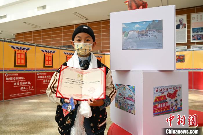 圖為一名獲獎學(xué)生與自己的繪畫作品合影?！≮w朗 攝