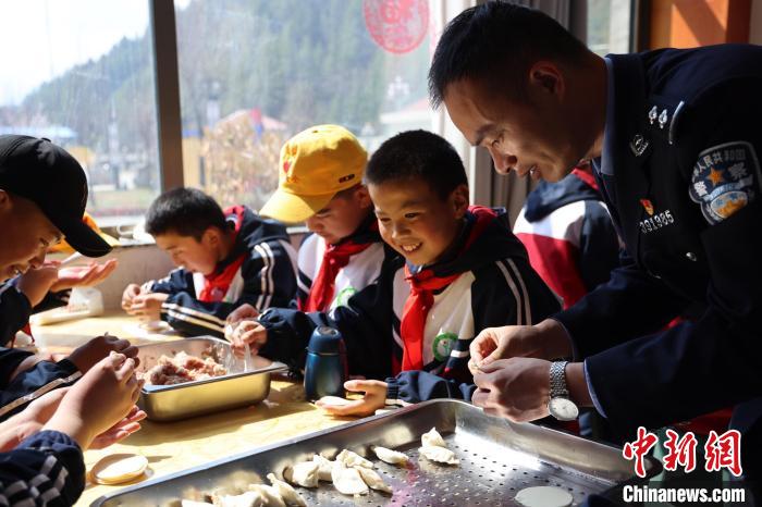 圖為亞?wèn)|邊檢站民警與駐地小學(xué)生其樂(lè)融融包餃子?！『?攝