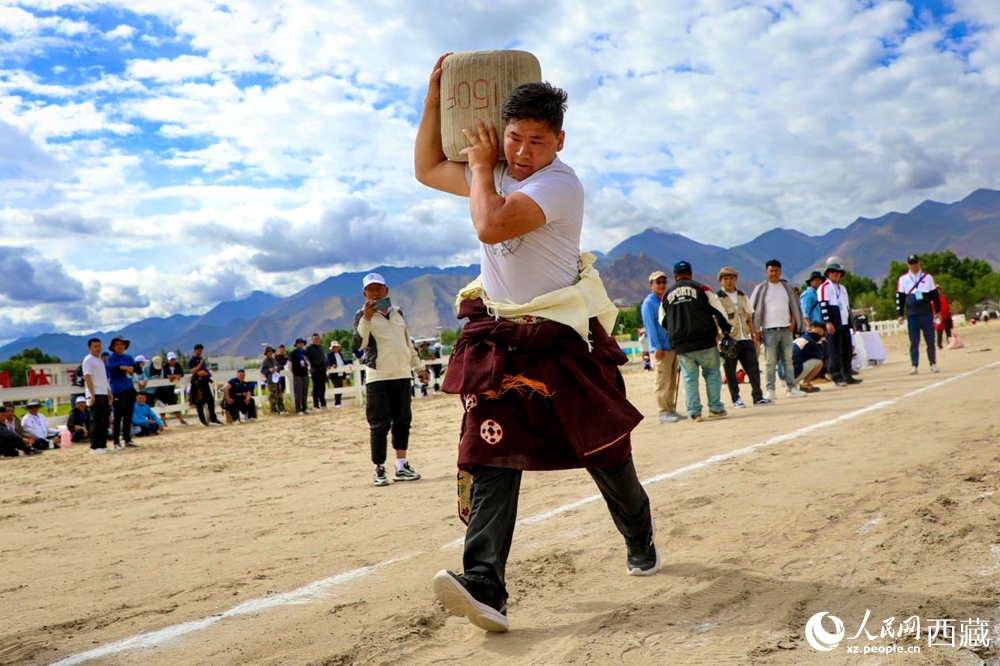 來(lái)自拉薩市當(dāng)雄縣的牧民選手將一塊150斤重的石頭扛在肩上飛奔。