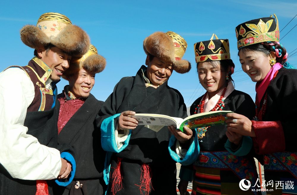 鄉(xiāng)親們身著民族盛裝，圍站在一起認(rèn)真翻看日歷，共話農(nóng)事安排與時(shí)節(jié)規(guī)律，笑容洋溢傳遞豐收期盼。人民網(wǎng)記者 吳雨仁攝