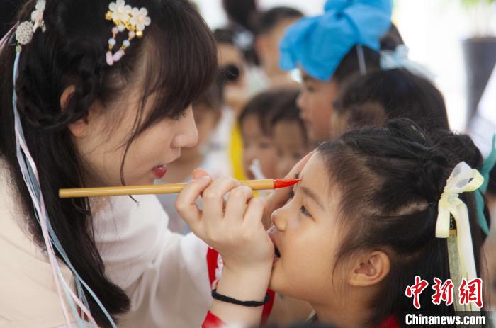 圖為老師在孩子們額頭上點上雄黃，驅(qū)邪辟禍?！《^生 攝